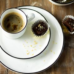 there is a cup of coffee and two pieces of cake on the plate next to each other