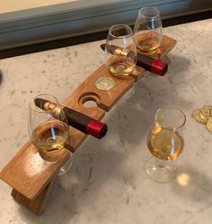 three glasses of wine are sitting on a wooden holder