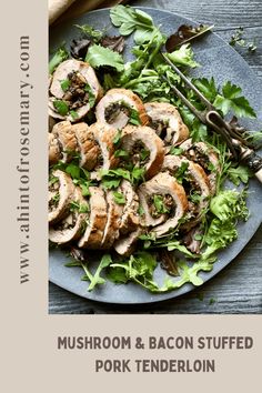 mushroom and bacon stuffed pork tenderloin on a blue plate with green salad leaves