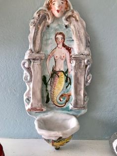 there is a ceramic statue with a mermaid on it