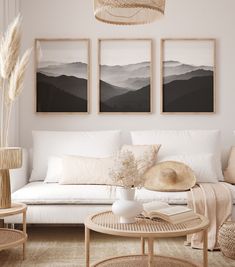 a living room filled with white furniture and paintings on the wall above it's coffee table