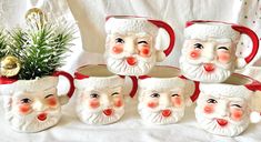 a group of santa claus mugs sitting next to a potted christmas planter