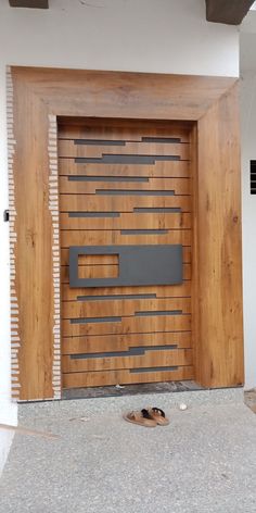 a pair of shoes sitting on the ground in front of a wooden door with horizontal slats