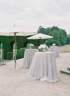 there are tables with umbrellas and flowers on the table in front of an outdoor area