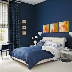 a bedroom painted in blue and white with a bed, desk, chair and pictures on the wall