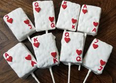 some white cake pops with red hearts and letters on them sitting on a wooden table