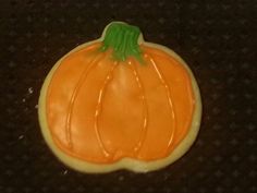 an orange decorated cookie sitting on top of a table