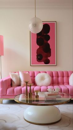 a living room with a pink couch and coffee table in front of a painting on the wall