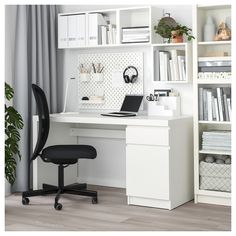 a desk with a laptop and bookshelf in front of it, next to a plant