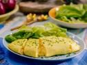 some food is on a white plate with lettuce and carrots in the background