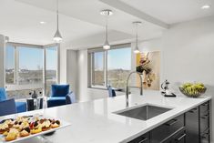 a kitchen with white counter tops and blue chairs in front of large windows overlooking the city