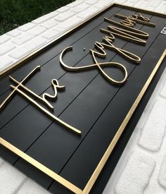 a black and gold business sign on the side of a white brick building with grass in the background