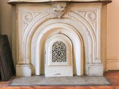 an ornate fireplace surround in a room with wood flooring and white painted stonework