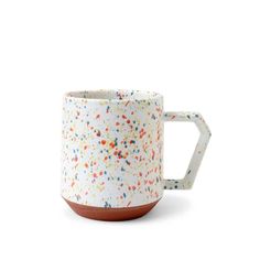 a coffee mug with sprinkles on the outside and inside, sitting on a white surface