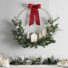 a christmas wreath hanging on the wall above a mantle with candles and decorations around it