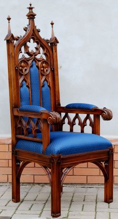 a wooden chair with blue upholstered seat and arm rests against a brick wall