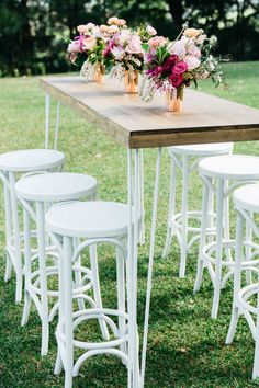 an outdoor table with stools and flowers on it