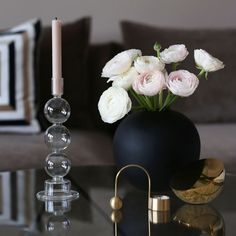 a glass table topped with a vase filled with white flowers next to a lit candle