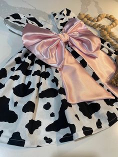 a cow print dress with a pink bow on it