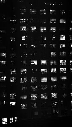 black and white photograph of multiple windows at night time, all lit up by the same light