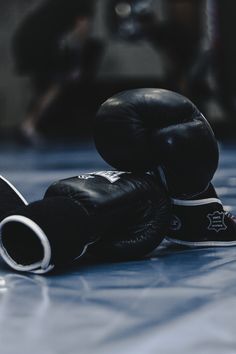 two black boxing gloves laying on the ground