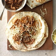 two tortillas on a cutting board with shredded cheese and meat in the middle