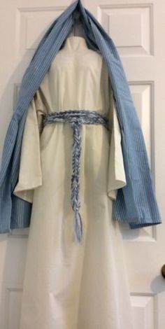 a white robe hanging on the door with a blue ribbon around it's neck