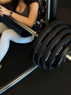 a woman is sitting on the ground with a barbell