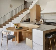 a kitchen with an island, table and chairs in front of the stairs that lead up to the second floor