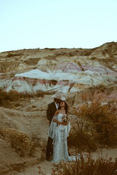 a man and woman standing next to each other in the desert