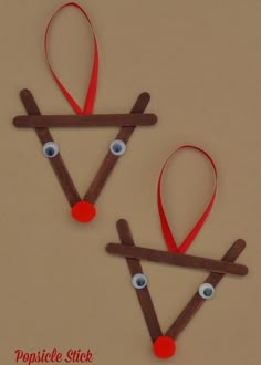 two reindeer ornament made out of sticks and yarn with eyes on them for christmas