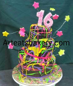 a birthday cake with stars and streamers on the top is decorated in neon colors