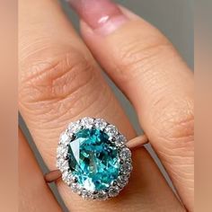 a woman's engagement ring with an aqua and diamond center