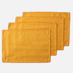 four yellow napkins with orange trim on them