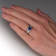 This delightful ring is centered with one (1) round mixed cut natural sapphire set into a half-bezel setting. The top face of the shank is accented with four (4), channel set, round brilliant cut diamonds. The ring measures 9.4mm at the top, rises 7.1mm above the finger, tapering to 3.4mm wide and 1.6mm thick at the base of the shank. This ring is currently a size 6.5. The sapphire shows light abrasions. Timeless Sterling Silver Sapphire Ring With Center Stone, Timeless Sapphire Ring With Sterling Silver, Platinum Sapphire Ring Round Cut, Diamond Ring With Brilliant Cut Sapphire In Round Shape, Luxury Round Stone Sapphire Ring For Anniversary, Sapphire Diamond Ring With Brilliant Cut, Elegant Sapphire Birthstone Ring With Brilliant Cut, Luxury Sapphire Birthstone Ring For Anniversary, Brilliant Cut Sapphire Diamond Ring