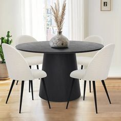 a black table with four white chairs around it and a vase on top of the table