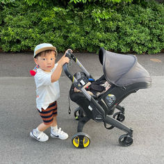 a little boy that is standing next to a stroller