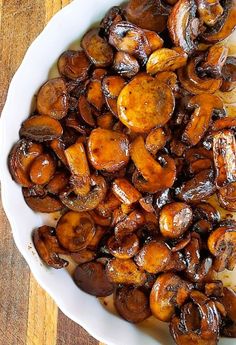 a white bowl filled with mushrooms on top of a wooden table