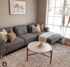 a living room with a couch, coffee table and rug in front of a window