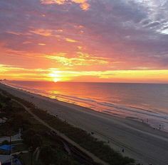 the sun is setting over an ocean beach