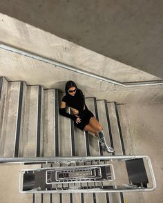 a woman sitting on top of an escalator next to a metal hand rail