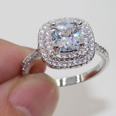 a person holding a ring with a large diamond in it's center and surrounded by smaller diamonds