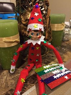 an elf is sitting on the table next to some christmas decorations