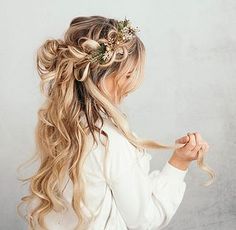 a woman with long blonde hair wearing a flower in her hair and braided into a half - up hairstyle