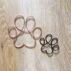 two pairs of scissors sitting on top of a wooden table next to an animal's paw