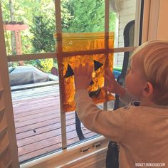 a young boy is looking out the window at something in the air that looks like an arrow