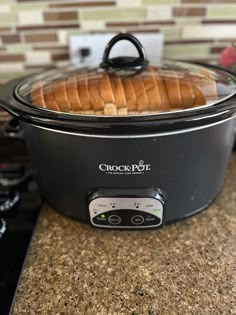 a crock pot with some bread in it sitting on a counter next to an oven