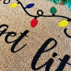 a welcome mat with the words enter gift on it and christmas lights all over it