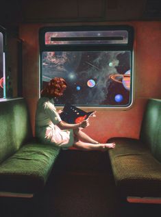 a woman sitting on a train reading a book while looking out the window at space