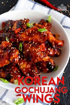 a white bowl filled with chicken wings covered in sesame seeds and garnishes